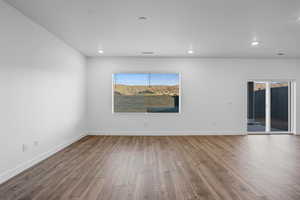Empty room with wood finished floors, plenty of natural light, recessed lighting, and baseboards