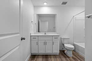Bathroom featuring toilet, vanity, wood finished floors, shower / bath combination, and baseboards