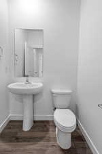 Bathroom with baseboards, toilet, wood finished floors, and a sink