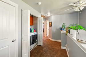 Washroom featuring washer and clothes dryer, dark colored carpet, baseboards, ceiling fan, and a textured ceiling