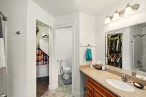 Bathroom with vanity, a spacious closet, toilet,  shower combination, and tile patterned floors