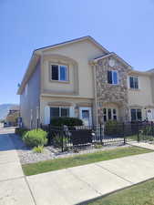View of front of property featuring stucco siding, a fenced front yard, stone siding, and a mountain view
