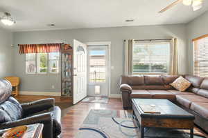 Living area with healthy amount of natural light, ceiling fan, and wood finished floors
