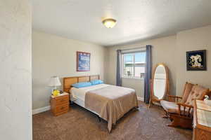 Carpeted bedroom with a textured ceiling and baseboards