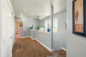 Hallway featuring carpet floors, a textured ceiling, and baseboards