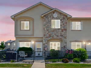 Townhome / multi-family property featuring stucco siding and stone siding