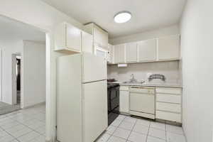 Kitchen featuring white appliances, a sink, light tile patterned floors, and light countertops