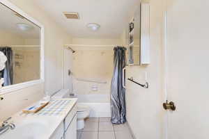 Bathroom with vanity, toilet, shower / tub combo with curtain, and tile patterned flooring