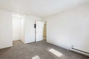 Carpeted spare room with a baseboard heating unit