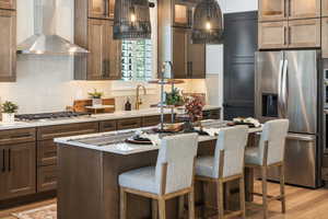 Kitchen featuring stainless steel appliances, wall chimney exhaust hood, glass insert cabinets, and backsplash