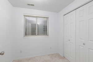Unfurnished bedroom with a closet, light carpet, and baseboards