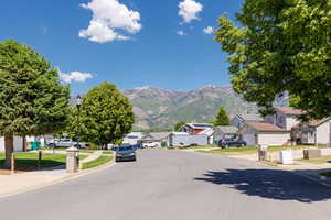 View of asphalt street featuring sidewalks, a residential view, curbs, street lighting, and a mountain view
