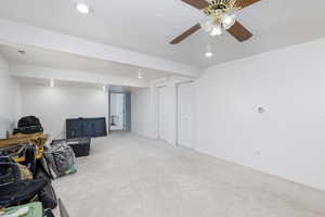 Finished basement with light colored carpet, recessed lighting, and a ceiling fan