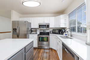 Kitchen with stainless steel appliances, a sink, light countertops, and white cabinets