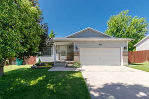 Single story home with driveway, a garage, and brick siding