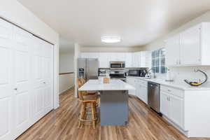 Kitchen featuring stainless steel appliances, a breakfast bar, and white cabinetry