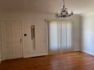 Living room with wood finished floors, baseboards, and a chandelier