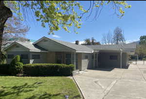 Ranch-style house featuring driveway, a front lawn, and an attached carport