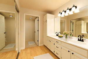 Bathroom with wood finished floors, double vanity, and baseboards
