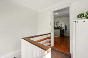 Hallway featuring an upstairs landing, wood finished floors, and crown molding