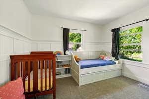 Carpeted bedroom with a decorative wall and wainscoting