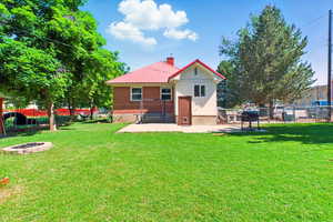 Back of house featuring an outdoor fire pit, a chimney, a patio, and metal roof