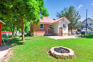 Rear view of house featuring a fire pit, a patio, metal roof, and brick siding