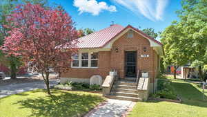 View of front of house with brick siding and metal roof