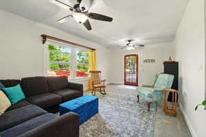 Living area with light colored carpet, ceiling fan, and baseboards