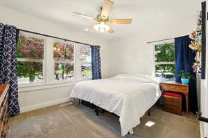 Carpeted bedroom with multiple windows, baseboards, and ceiling fan