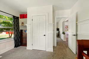 Unfurnished bedroom featuring carpet floors, multiple windows, a decorative wall, and wainscoting