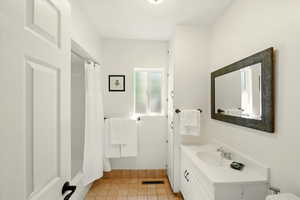 Bathroom featuring vanity, tile patterned flooring, shower / bath combination with curtain, and baseboards