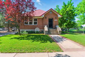 View of front of house featuring brick siding and metal roof