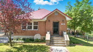 View of front of property featuring brick siding and metal roof