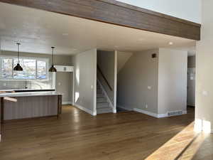Kitchen featuring decorative light fixtures, light wood-style floors, white cabinetry, open floor plan, and a kitchen breakfast bar