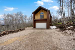 View of front of home featuring dirt driveway and a garage