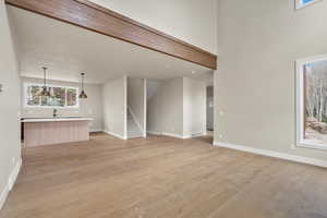 Unfurnished living room with light wood-style floors, baseboards, stairs, a sink, and recessed lighting