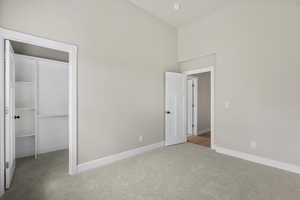 Unfurnished bedroom featuring carpet flooring, a spacious closet, baseboards, and a closet