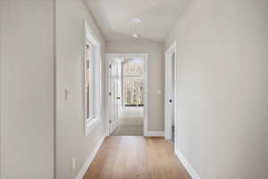 Hallway with light wood-style flooring and baseboards