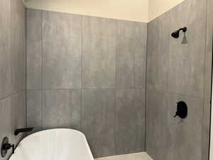 Full bath featuring a freestanding bath and a tile shower
