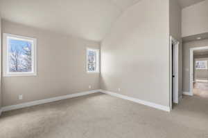Unfurnished room featuring light colored carpet, baseboards, and high vaulted ceiling