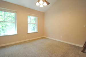Spare room featuring carpet floors, ceiling fan, lofted ceiling, and baseboards
