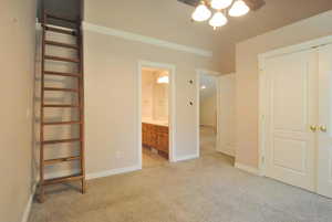Unfurnished bedroom featuring light carpet, baseboards, and ensuite bath