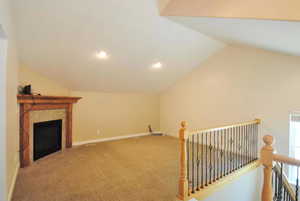 Bonus room with carpet, a tiled fireplace, vaulted ceiling, baseboards, and recessed lighting