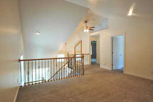 Carpeted empty room featuring ceiling fan, lofted ceiling, and baseboards