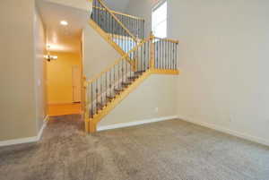 Stairs featuring carpet flooring, baseboards, and a chandelier