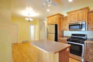 Kitchen featuring stainless steel appliances, a kitchen island, a chandelier, recessed lighting, and light wood finished floors