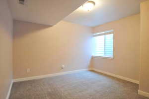 Carpeted spare room featuring baseboards