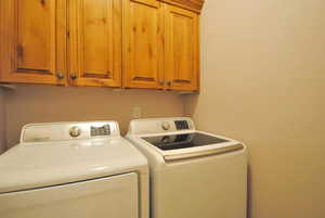 Washroom featuring separate washer and dryer and cabinet space