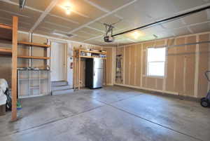 Garage with freestanding refrigerator and a garage door opener